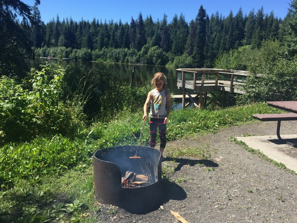 Girl roasting a hot dog over a campfire