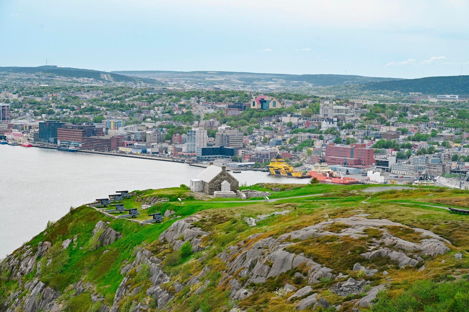 looking down at the queens battery and barracks, as well as the cannons at Signal Hill National Historic Site, the town of st. john's is in the background