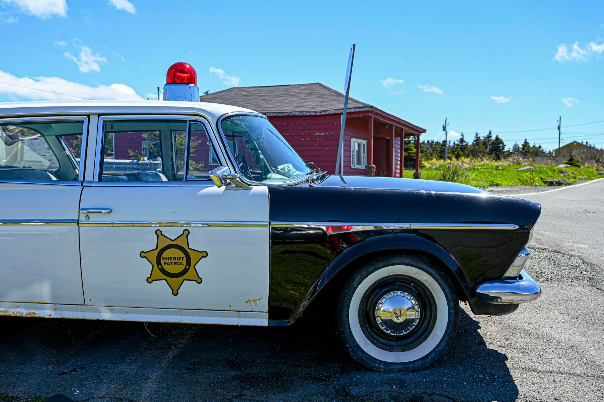a vintage sheriff patrol car sits on the side of the road beside a historic building in st. john's newfoundland