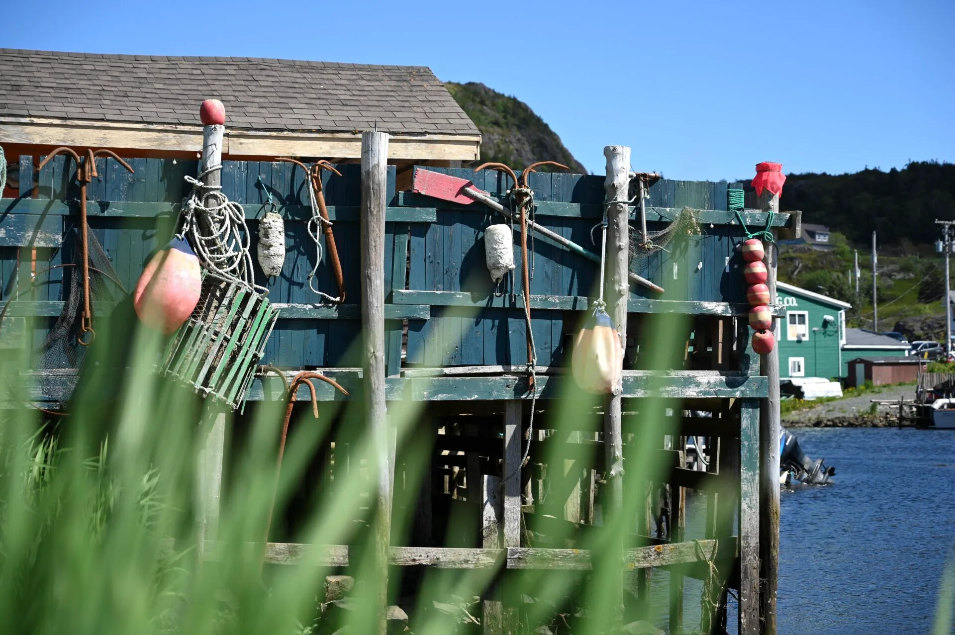 various old pieces of fishing gear hanging on a green fence in quidi vidi village