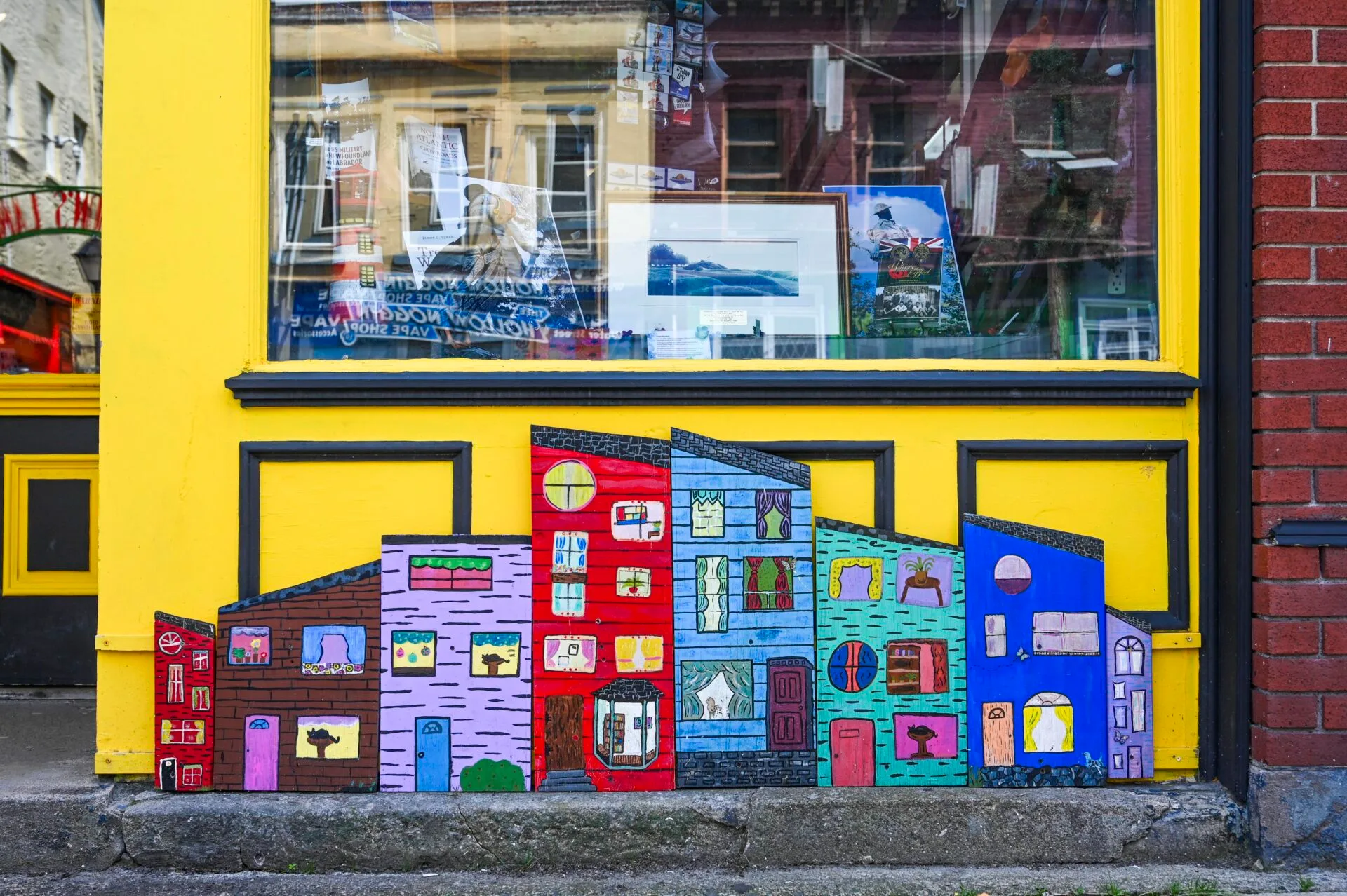 a small mural depicting colourful buildings is painted under the window of a storefront in downtown st. john's