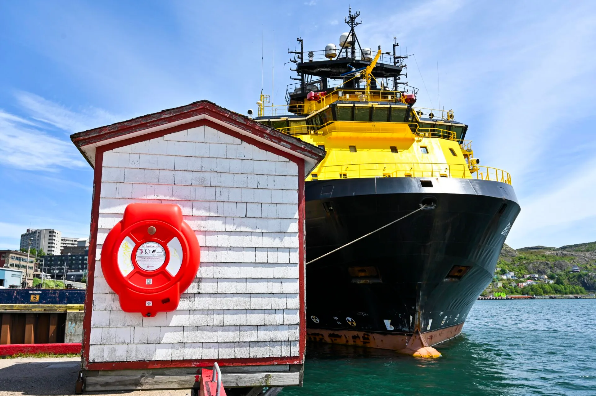 a large black and yellow ship sits docked inside st.john's harbour