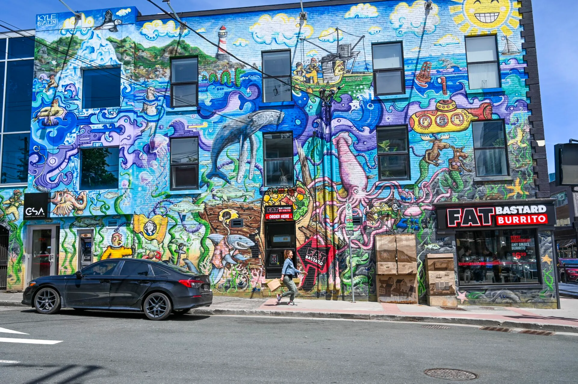 a woman walks past a brightly coloured ocean themed mural in downtown st.john's newfoundland