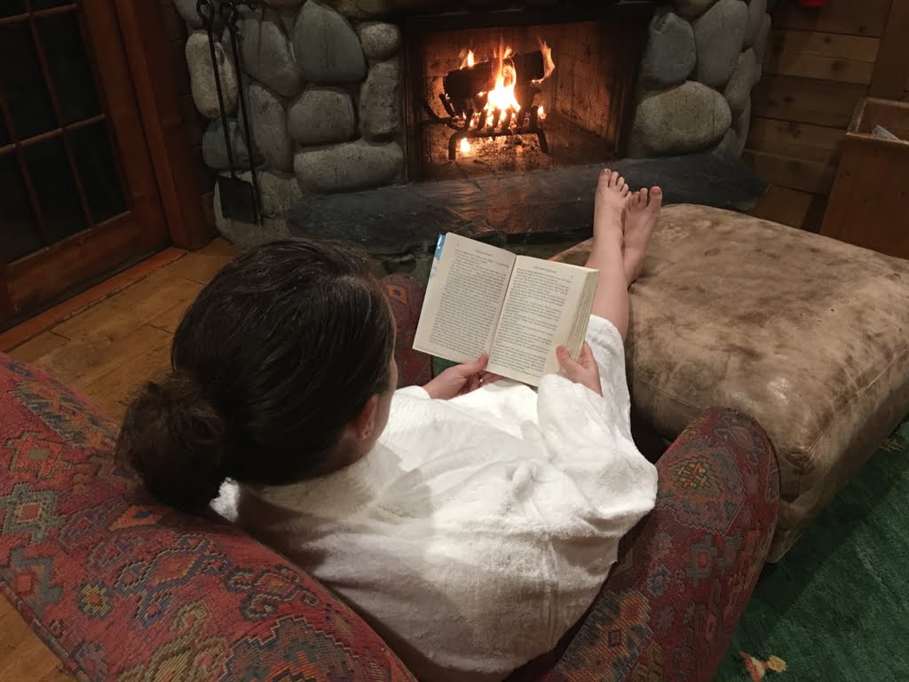Woman lounging in front of fire at Rowena's Inn Cabins