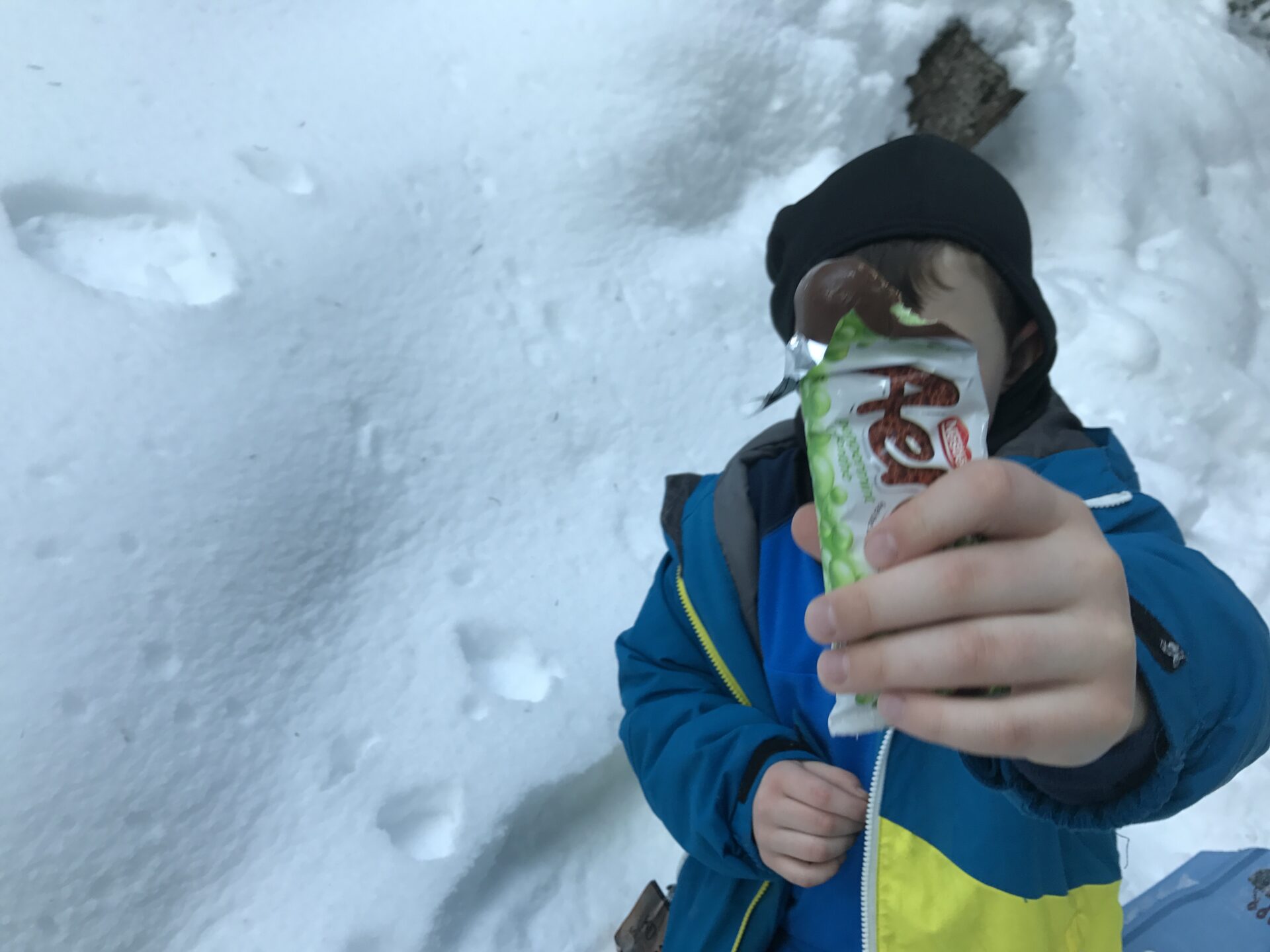 boy-holding-chocolate-bar-on-snowshoe-hike
