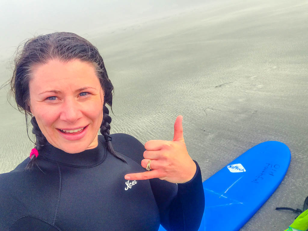 Jami Savage on the beach with a surfboard for her Tofino Surf School review
