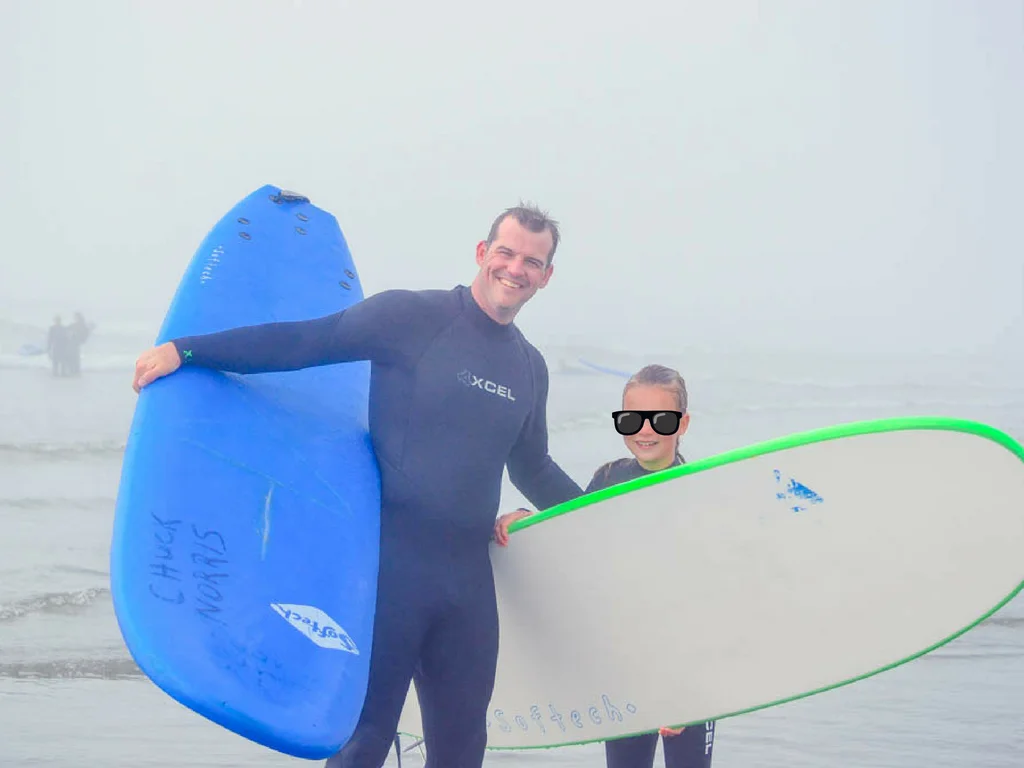 Man and girl on beach in Tofino with surfboards