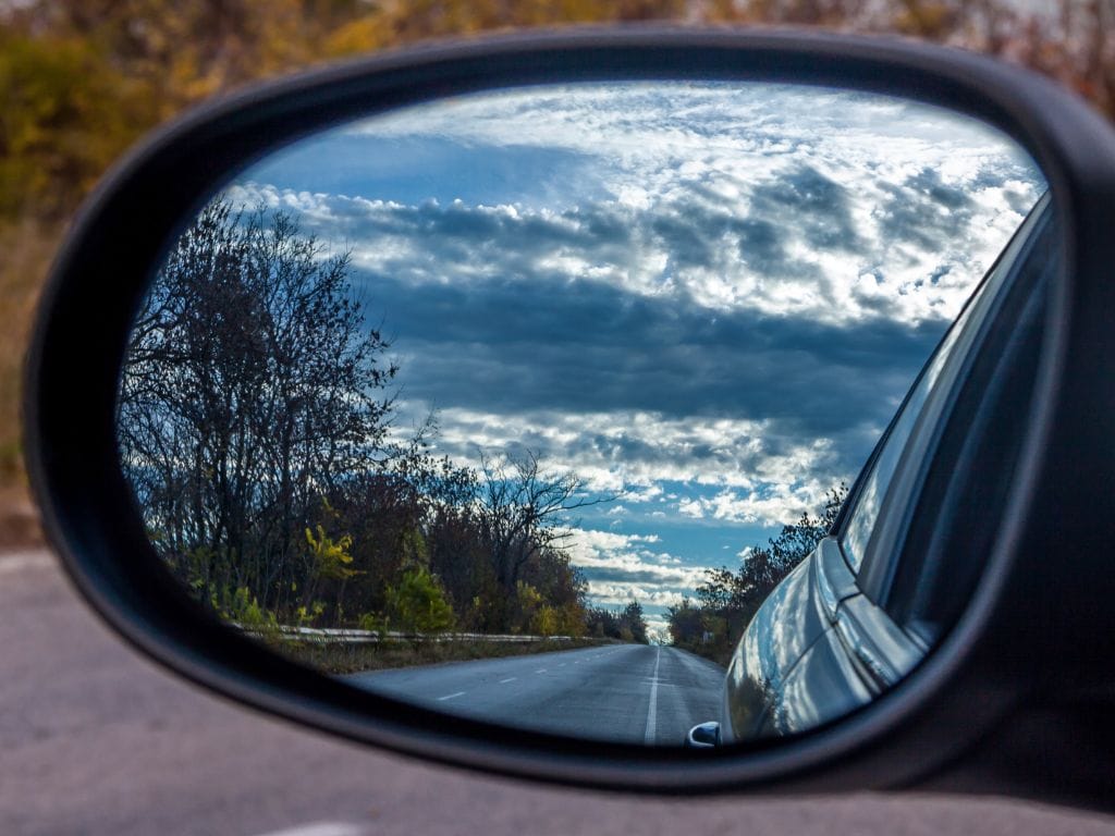 view of a highway road, taken in the reflection of a cars sideview mirror