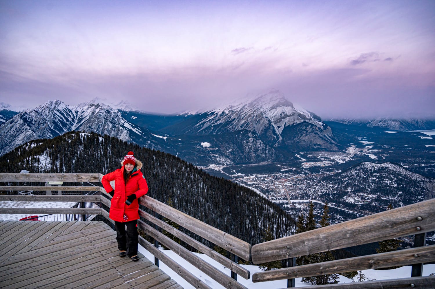woman wearing a red coat stands at the top of the boardwalk at the banff gondola