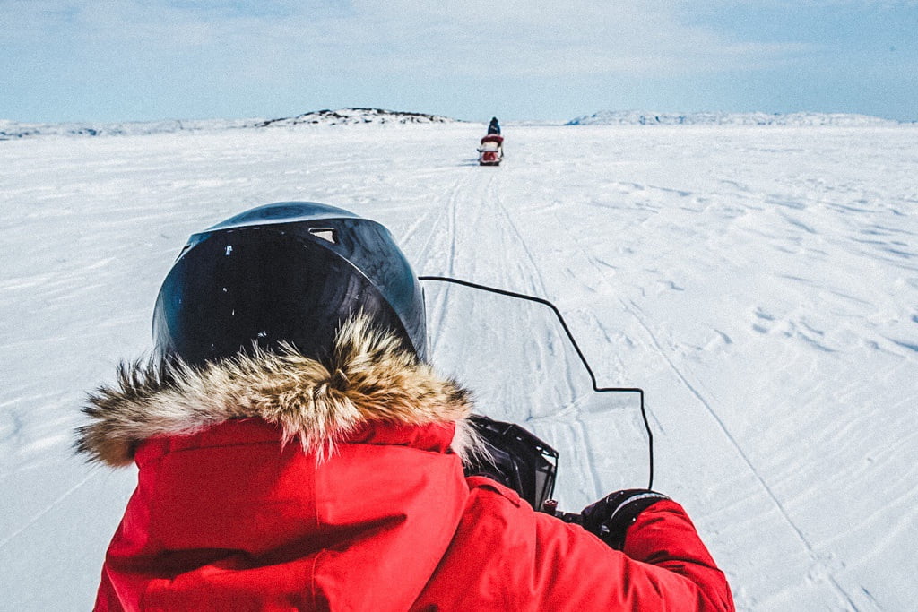 Jami Savage on sled snowmobiling through the Arctic
