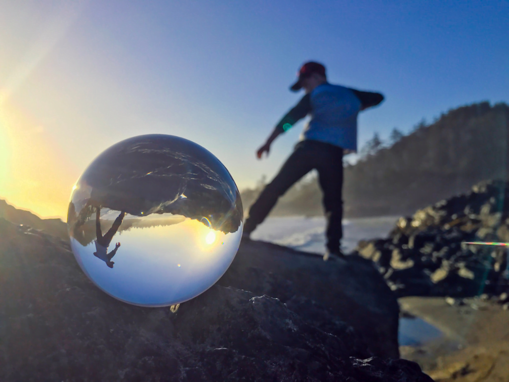 reflection on lensball of child playing on the rocks in tofino 