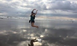 Jami Savage jumping on a beach