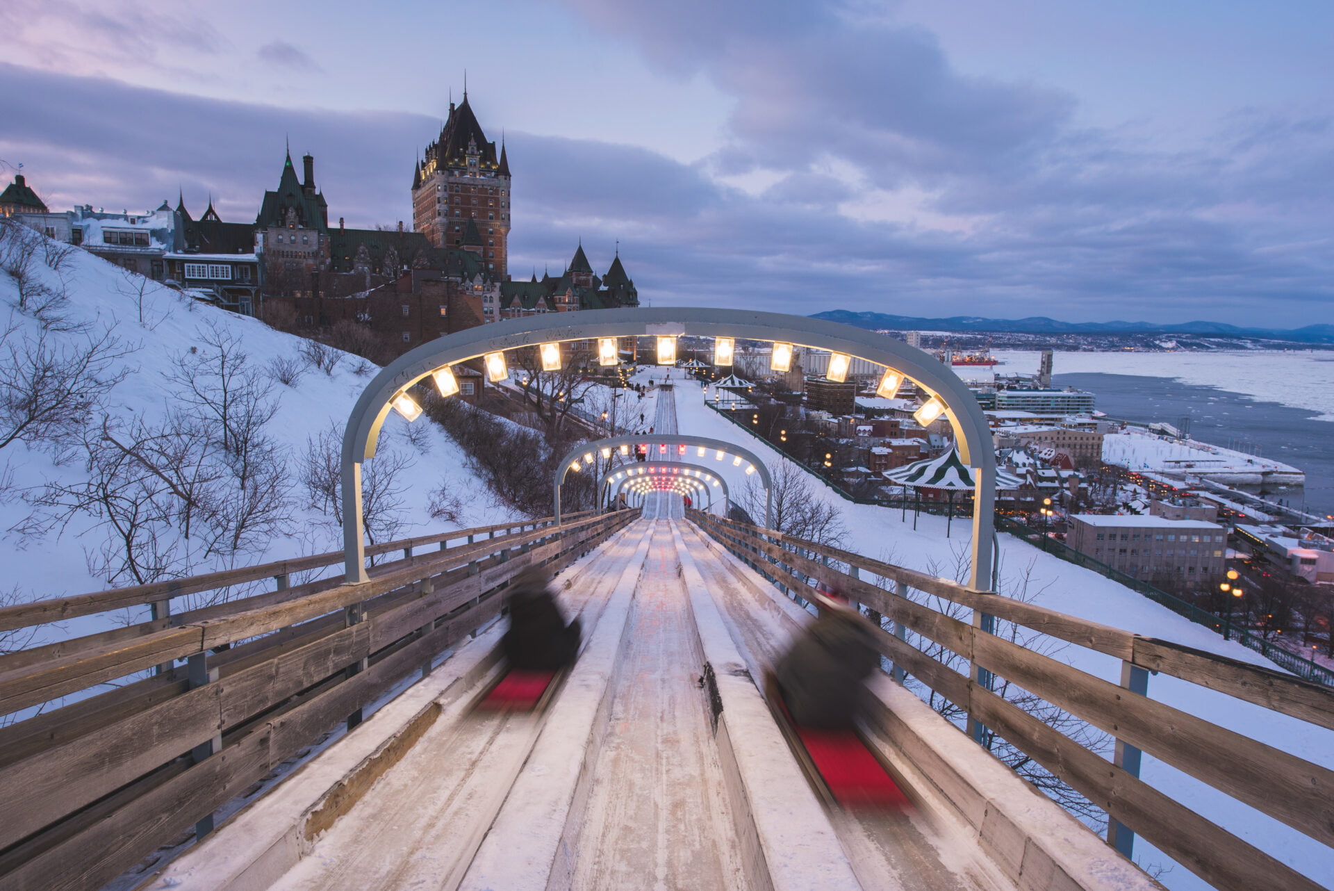 two people sliding down large snow slides at carnaval de quebec