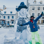 girl standing in front of a bonhomme ice sculpture at carnaval de quebec