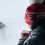 Boy drinking hot chocolate and looking out a window after ice fishing Laval