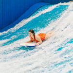 jami savage lying on stomach on surfboard at laval indoor surfing