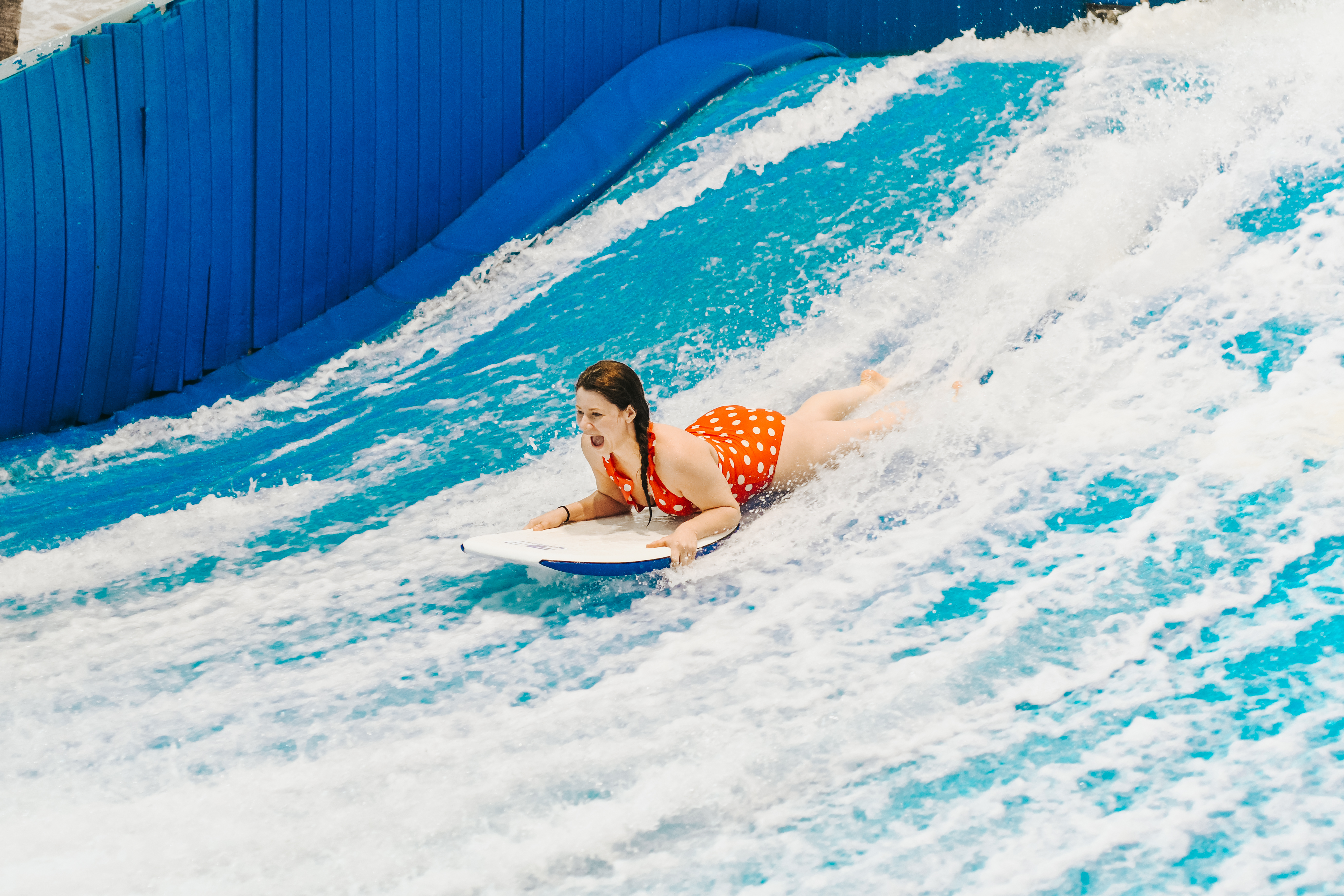 jami savage lying on stomach on surfboard at laval indoor surfing