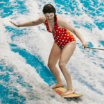 jami savage standing up on a surf board at laval indoor surfing