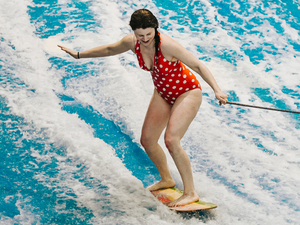 jami savage standing up on a surf board at laval indoor surfing