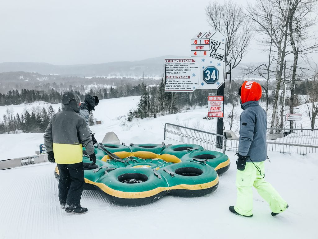 family getting ready to hop inside a multi-person snow rafting tube.