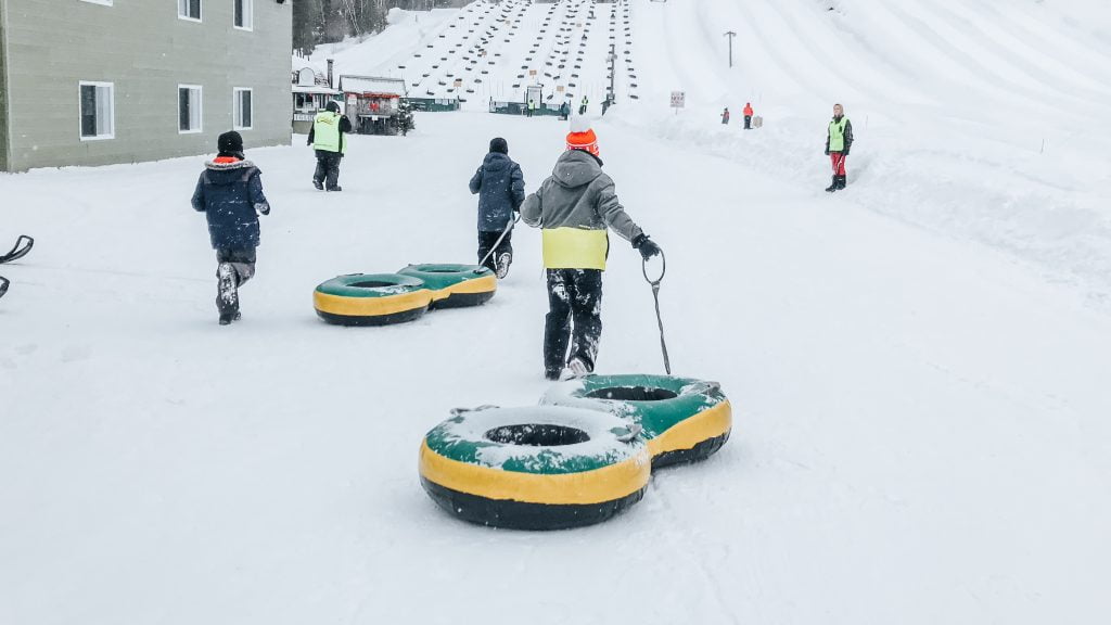 Child pulling a two person snow tube at a snow tubing park Montreal