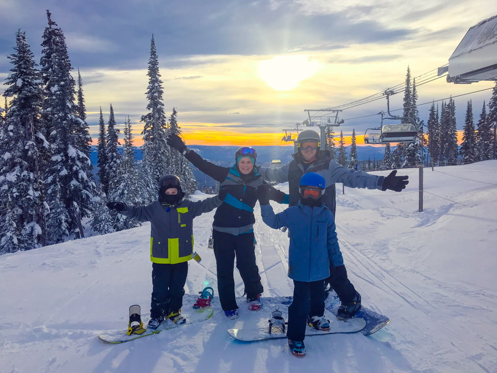 Jami Savage posing with family on the top of a ski mountain