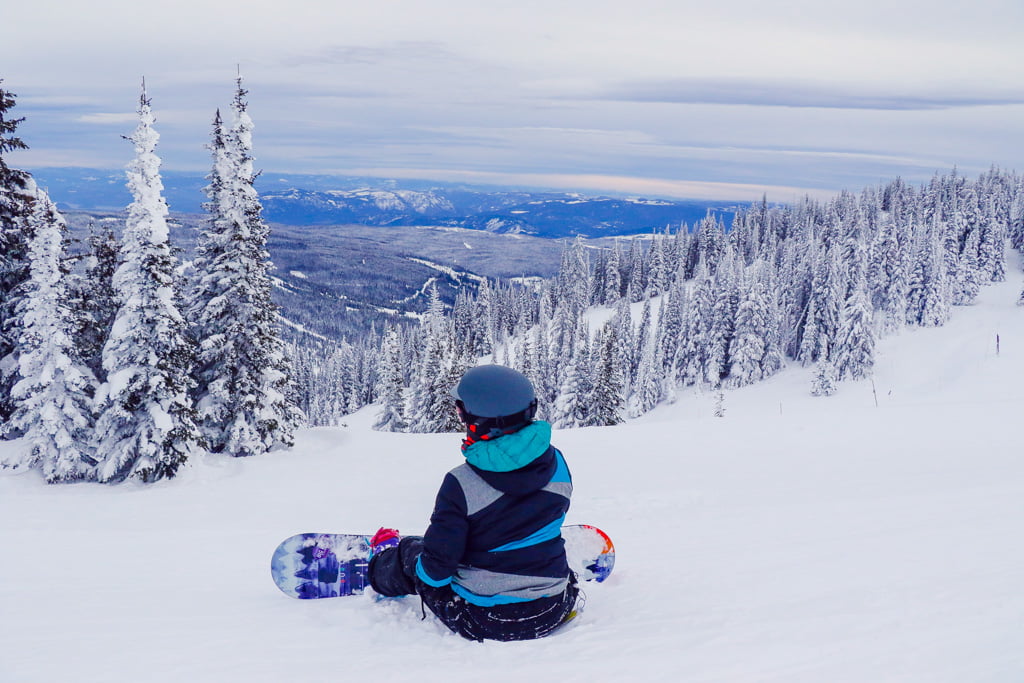 Jami Savage sitting on a ski-hill with snowboard