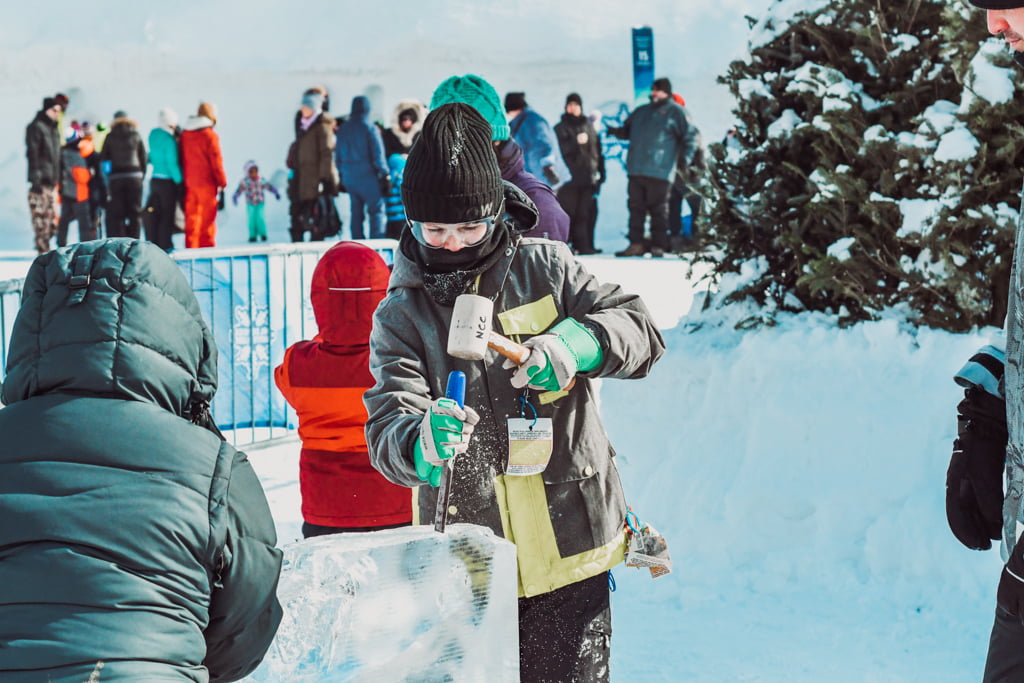 boy using a chisel and mallet on a large block of ice at winterlude guide