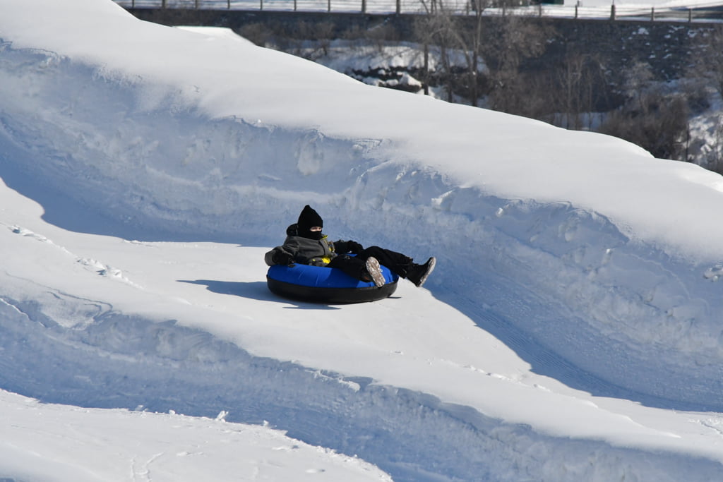 boy tubing down snow covered hill at winterlude guide