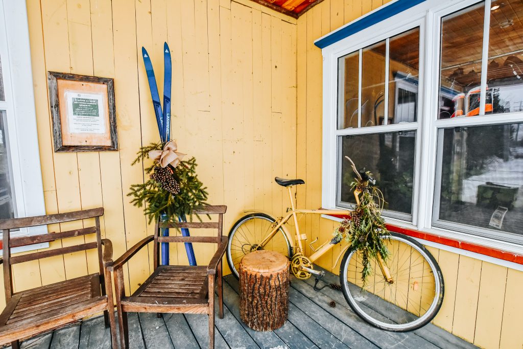 Porch with two chairs, skis, and a bike on it