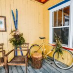Porch with two chairs, skis, and a bike on it