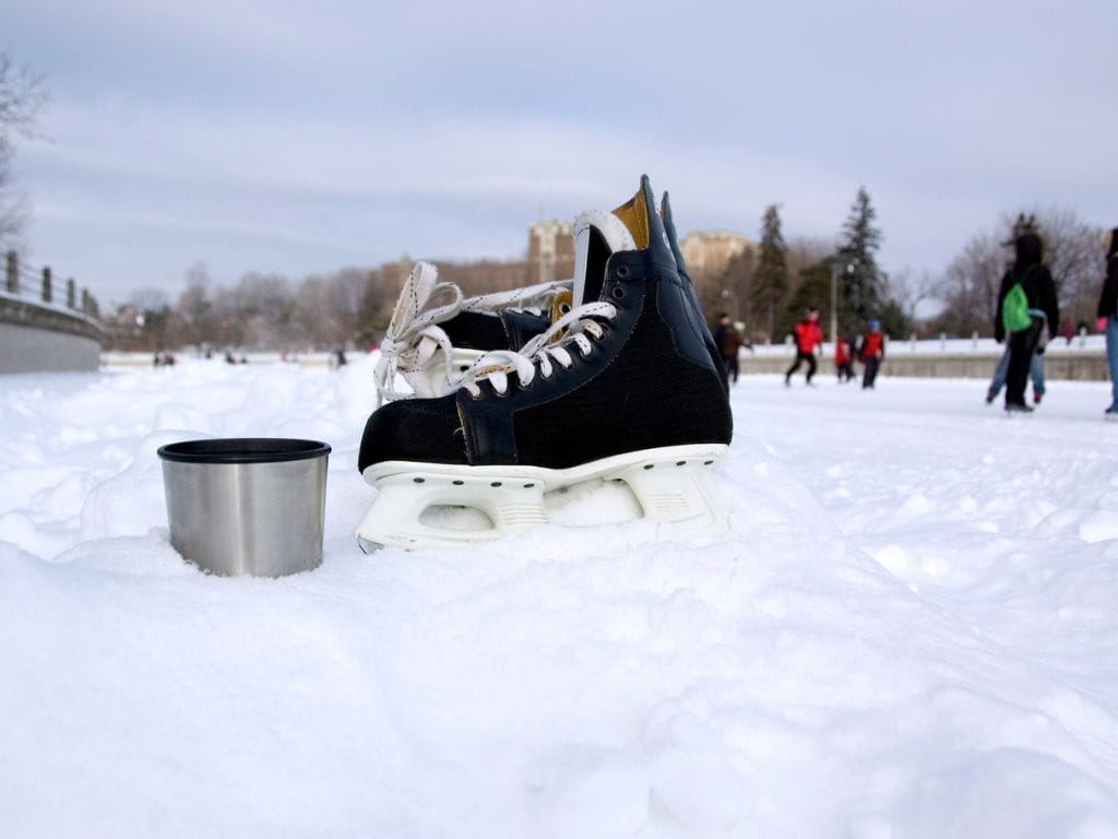 close up of a hockey skate and a cup of hot chocolate, people are skating on the rideau canal