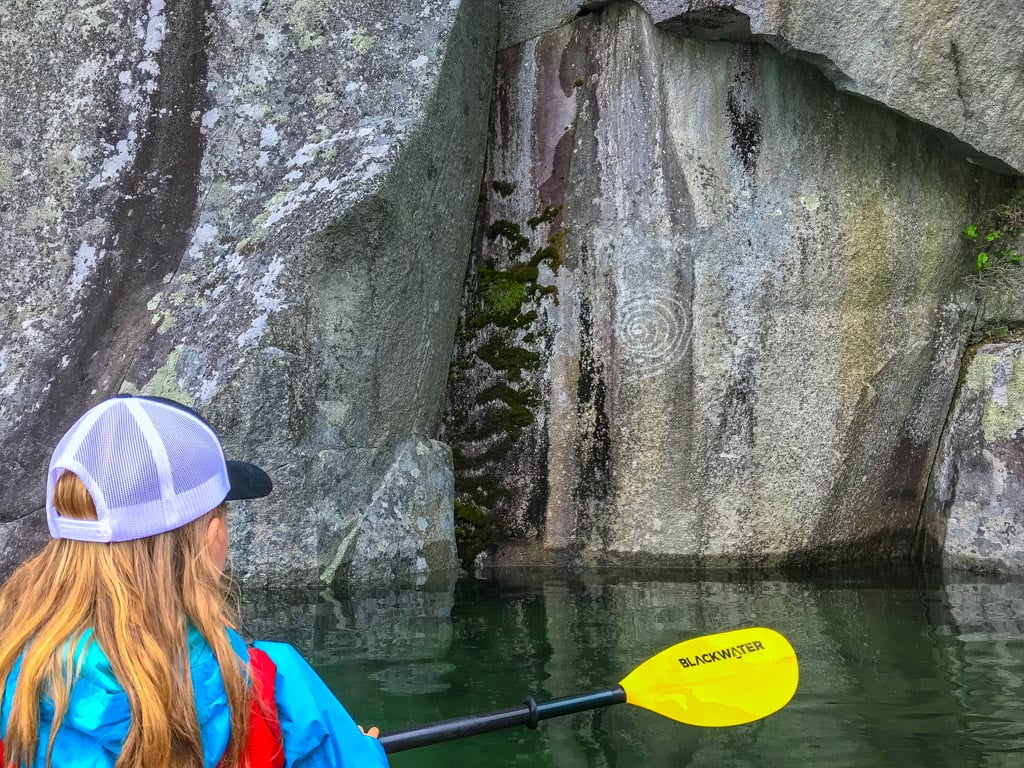 Girl looking at aboriginal pictographs during her Harrison Lake kayaking adventure