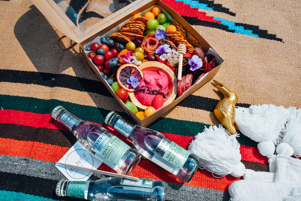picnic blanket with graze box and drinks sitting on it