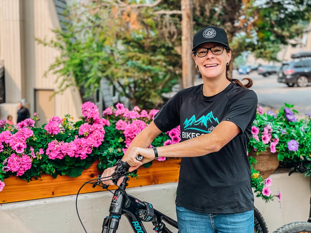 woman standing next to a mountain bike in front of a flower planter