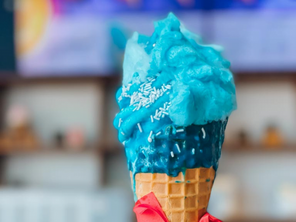 blue ice cream in a waffle cone dipped in blue chocolate and sprinkles