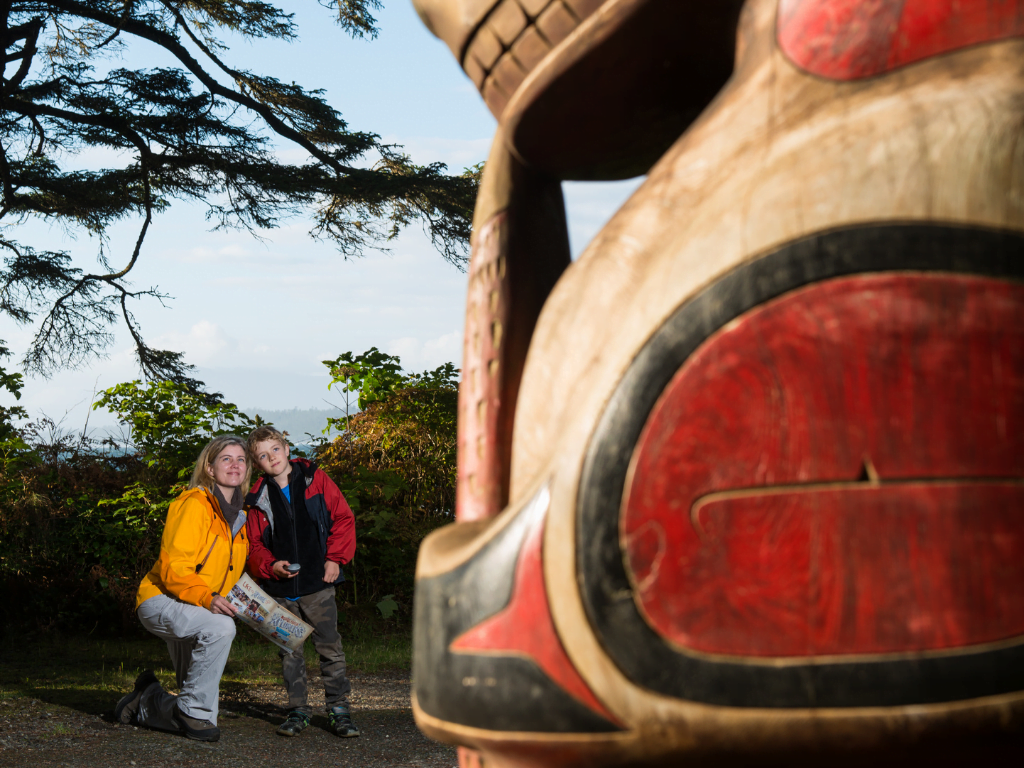 a woman and child admire a totem pole from a distance