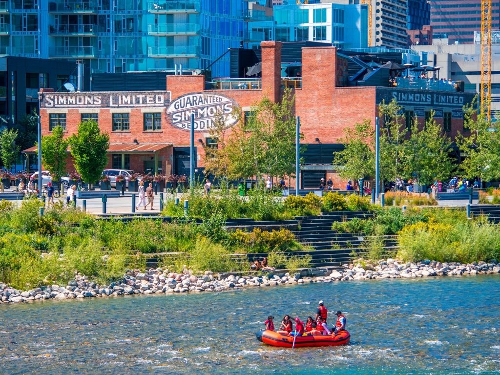 raft floating down the bow river with downtown calgary in the background