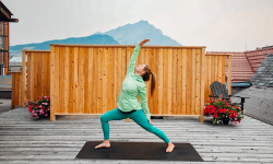 woman doing yoga on a wood deck with a mountain off in the distance behind her