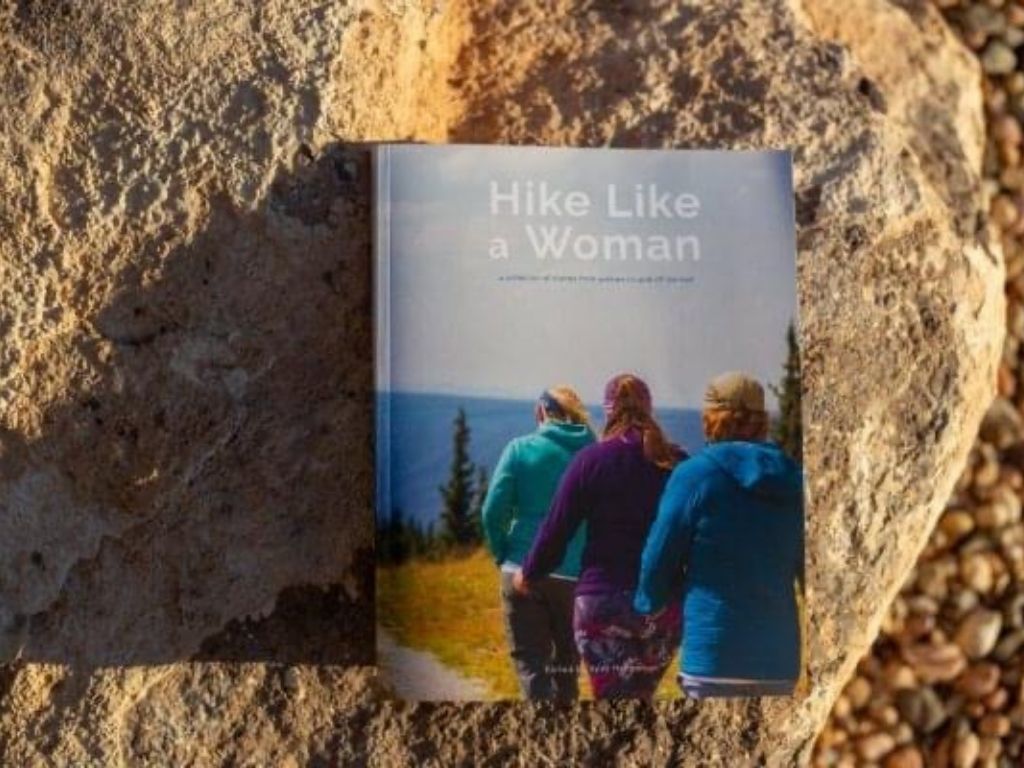 hike like a girl book sitting on a large rock in the sunshine