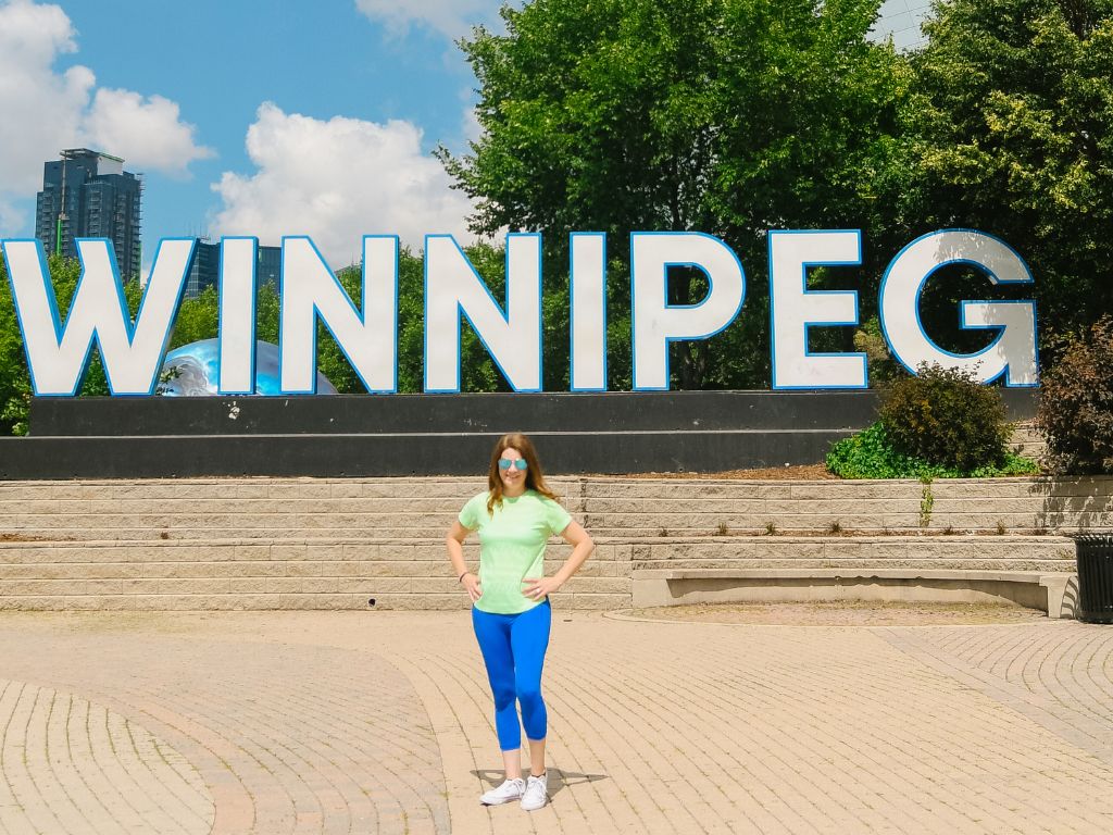 woman standing in front of winnipeg sign on Family Trip to Winnipeg