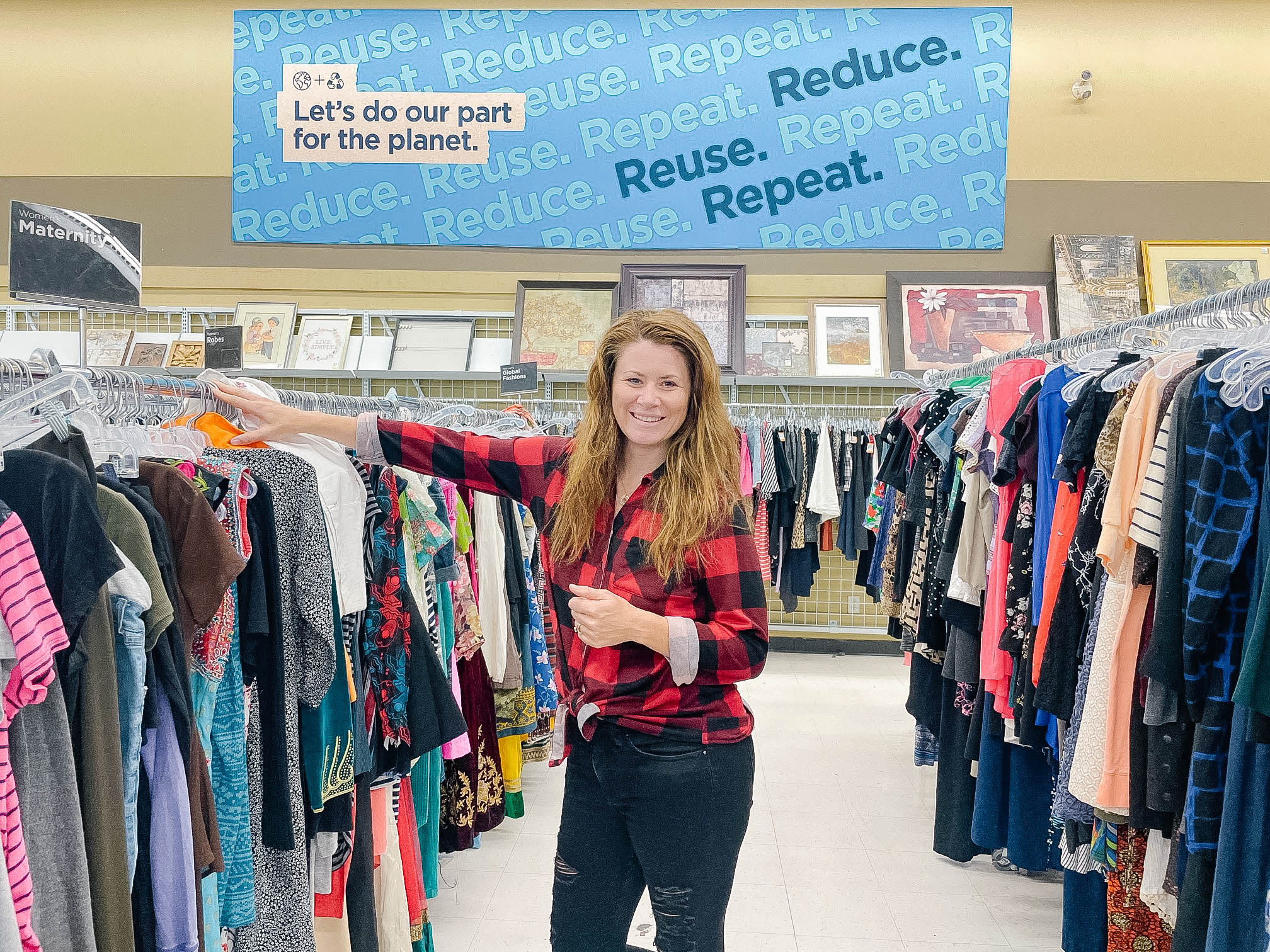 woman standing in an aisle between racks of clothing in a thrift store as Ways to Save Money For Back To School Season