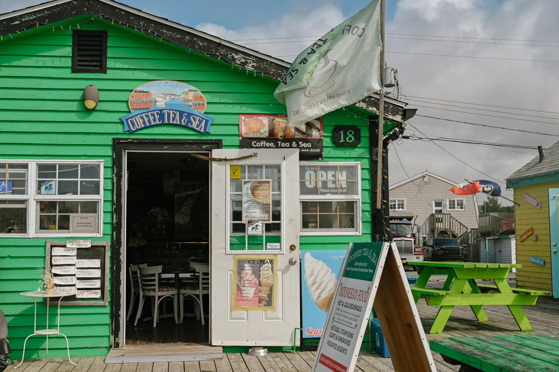 front entrance of the coffee, tea and sea cafe on the boardwalk of fisherman's cove nova scotia, it is bright green building
