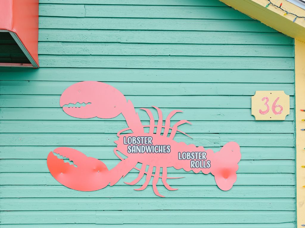 teal building with a pink lobster advertising lobster sandwiches and lobster rolls