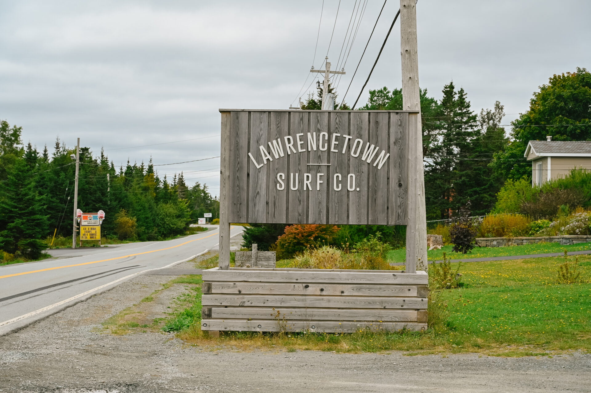 wooden sign beside the road that reads lawrencetown surf co.