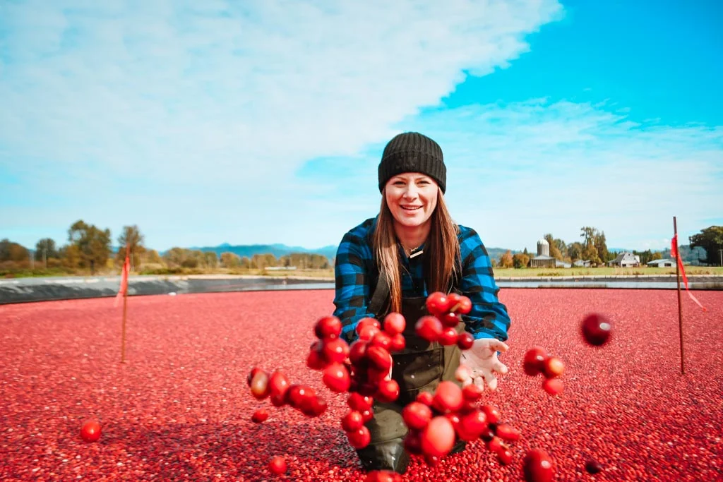 woman doing the cranberry plunge langley and throwing cranberries at the camera