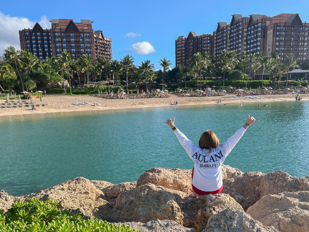 is blogging worth it? jami sits on the beach of hawaii looking at the disney aulani resort