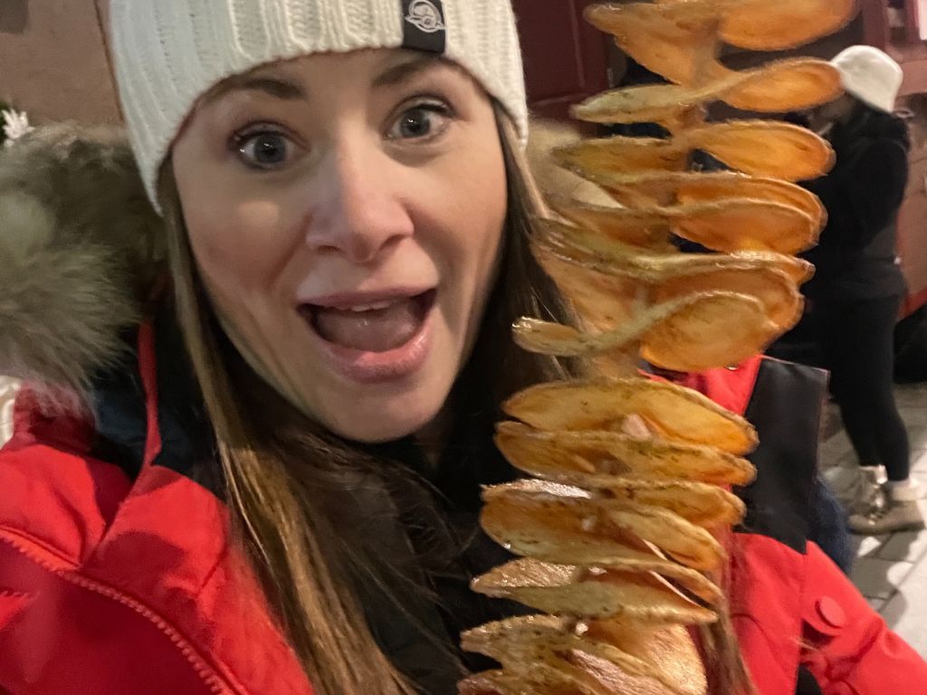 woman excited about a tornado potato snack at the ottawa christmas market - what to do in Ottawa in November