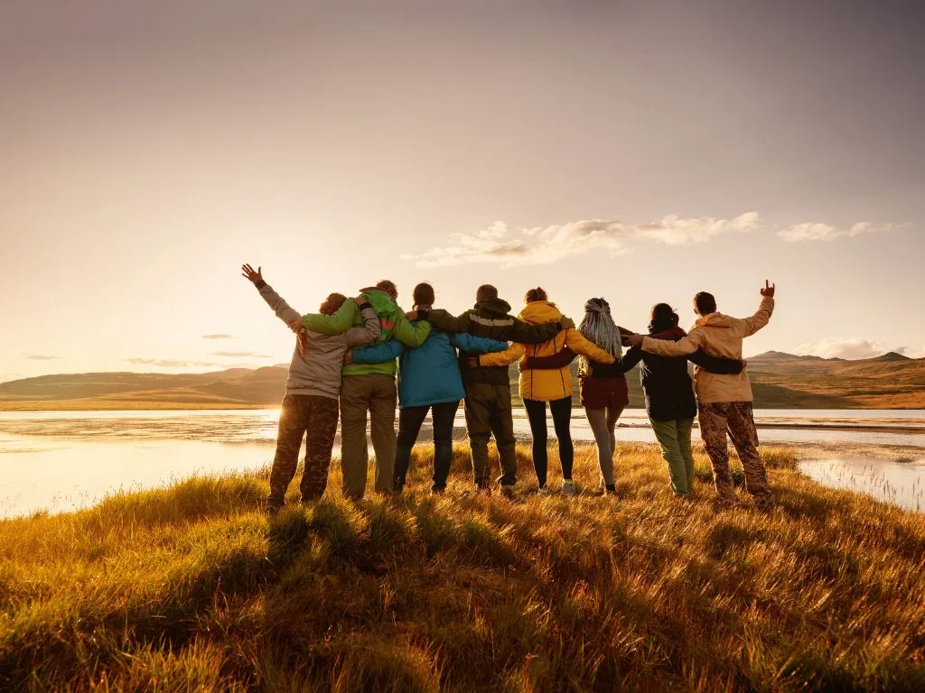 a large family stands with their backs to the camera, their arms are intertwined and they are looking out at the view
