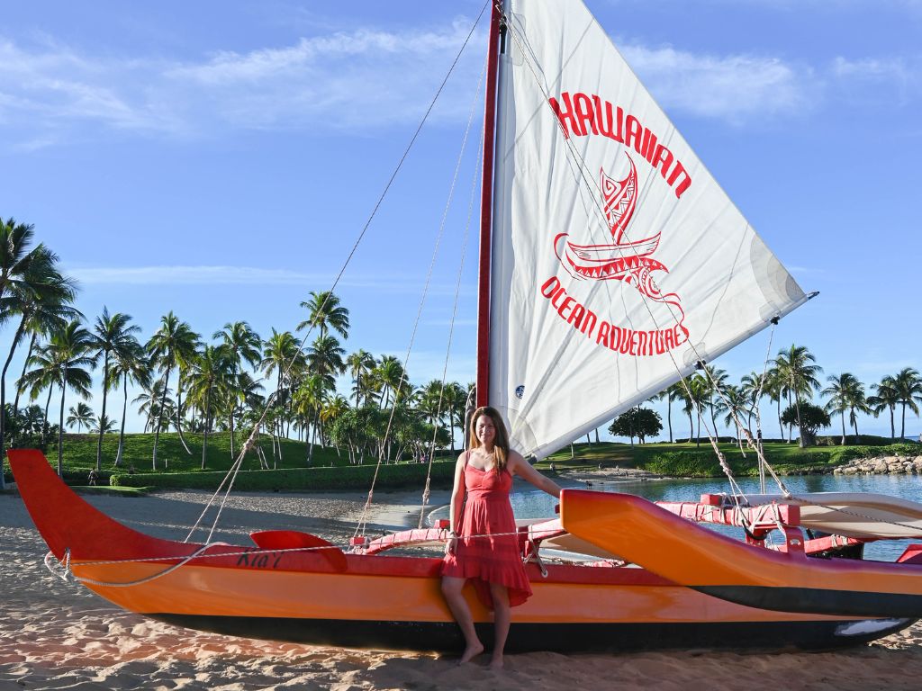jami standing in front of a traditional hawaiian canoe on the beach at aulani a disney resort and spa